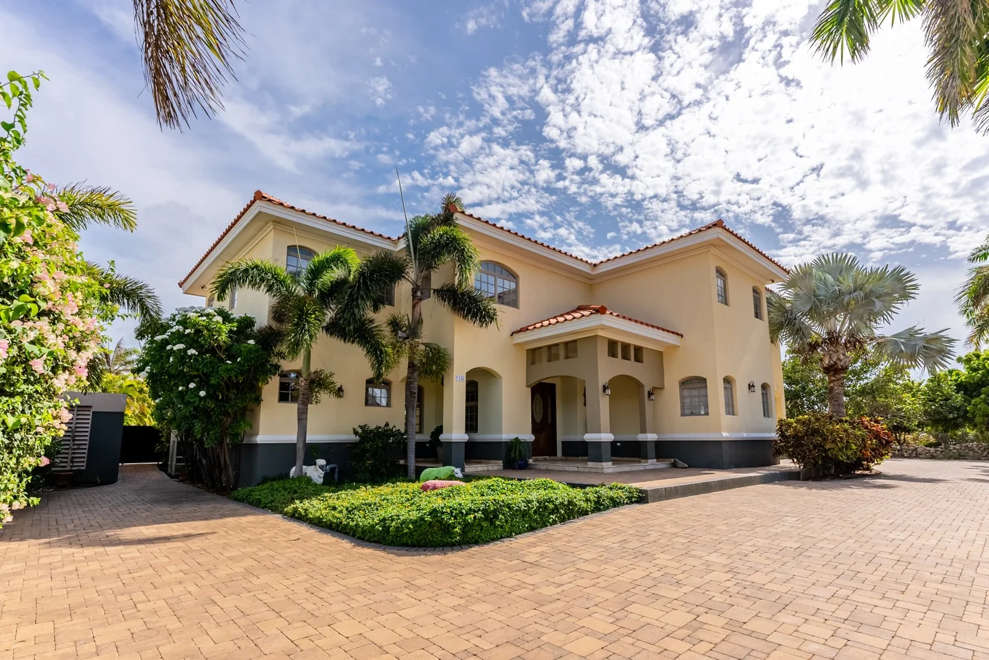 Malmok 532 E front facade framed by palms and flowering gardens — original listing photograph