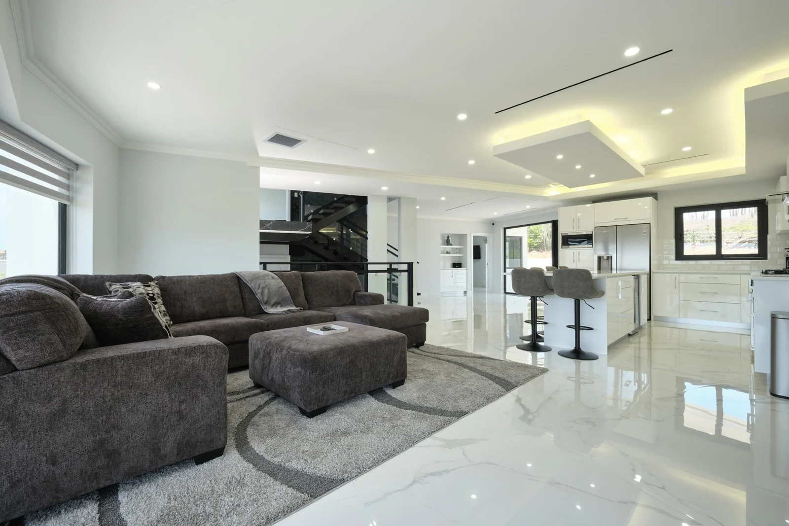 Canto di Lama 44 living room with a large sectional sofa, pale stone floors and an open-plan kitchen